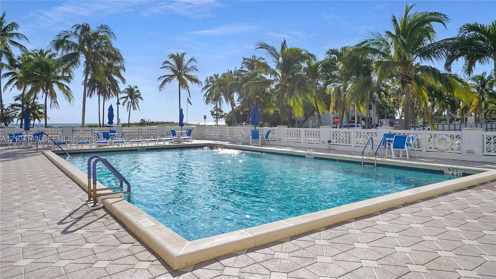 111 N Pompano Beach Boulevard, #304, Pompano Beach, FL 33062 Swimming pool featuring a concrete deck, metal handrails, a geometric tile border, and a perimeter balustrade