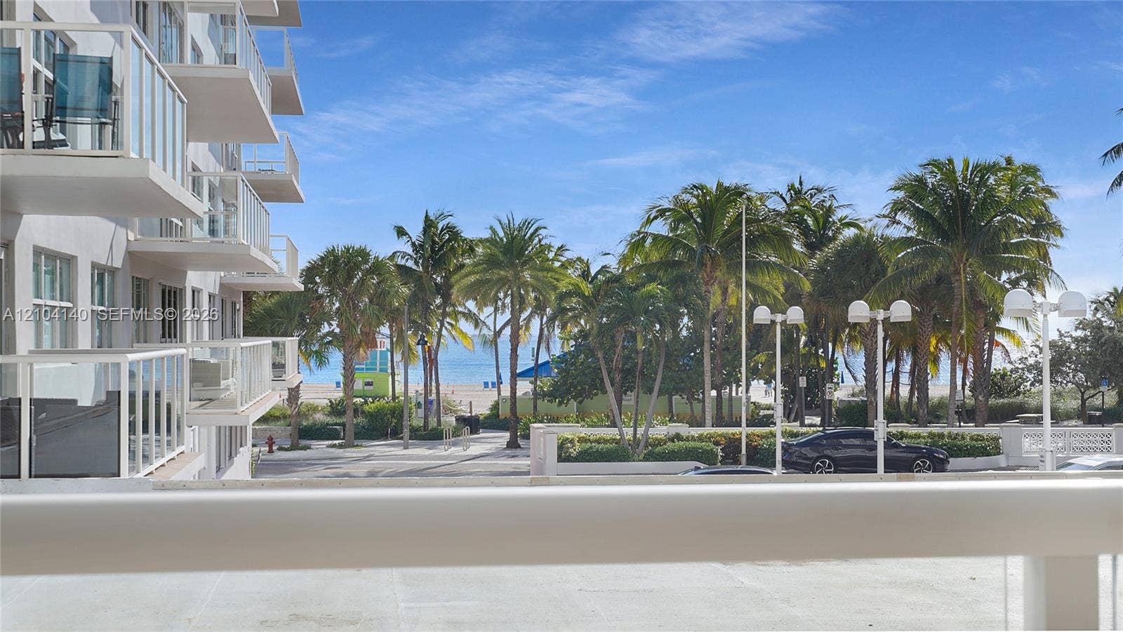 111 N Pompano Beach Boulevard, #304, Pompano Beach, FL 33062 Private balcony featuring glass railings, overlooking palm trees and coastal scenery