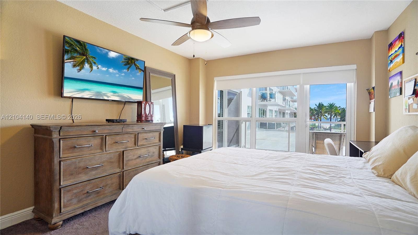 111 N Pompano Beach Boulevard, #304, Pompano Beach, FL 33062 Room featuring a ceiling fan with integrated lighting, carpeted flooring, and glass doors leading to a balcony