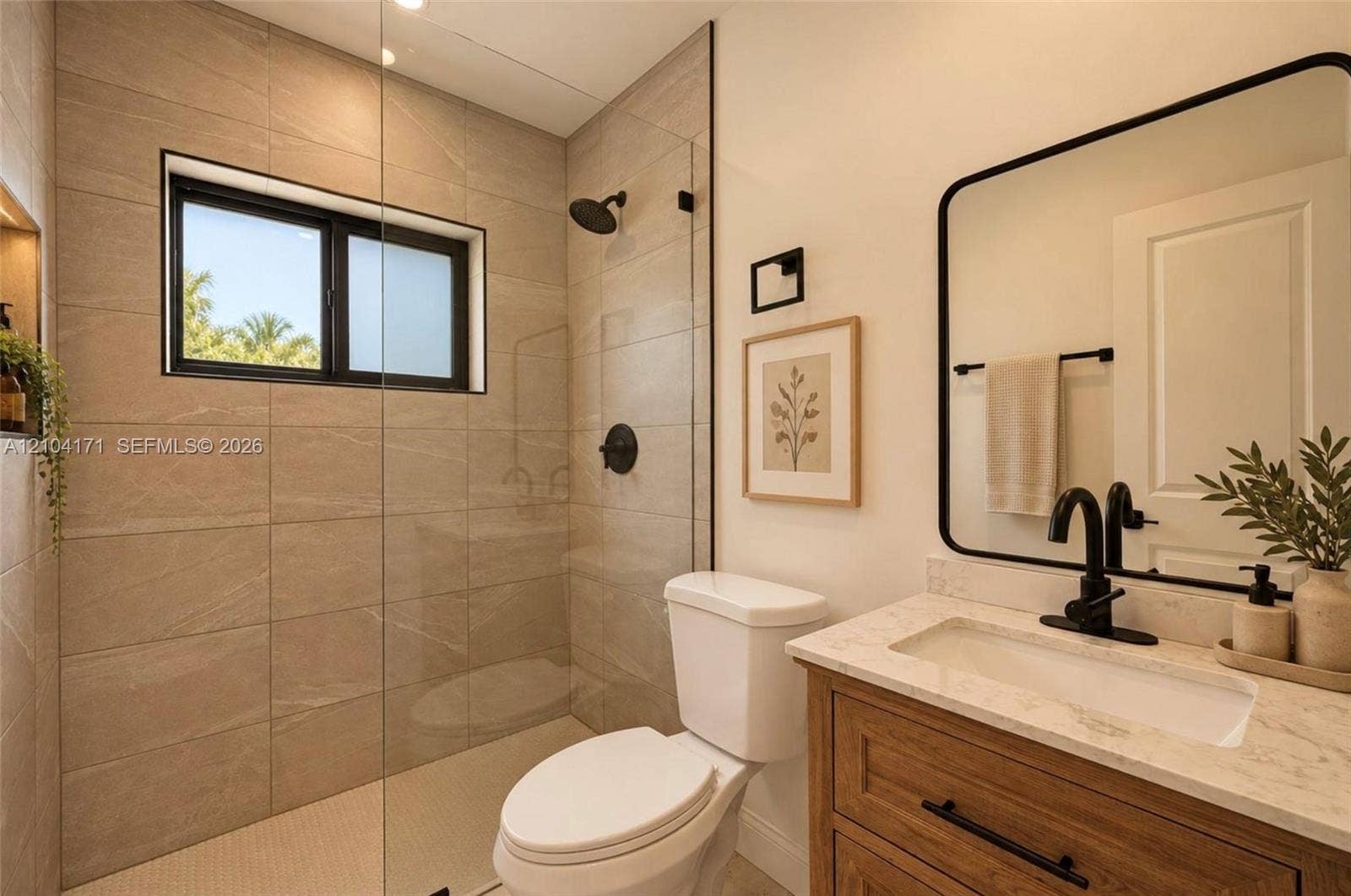 745 NW 32nd Avenue, Miami, FL 33125 Bathroom featuring a glass-enclosed shower with floor-to-ceiling large-format tiling, wood-finish vanity with stone countertop, matte black fixtures, and a framed mirror
