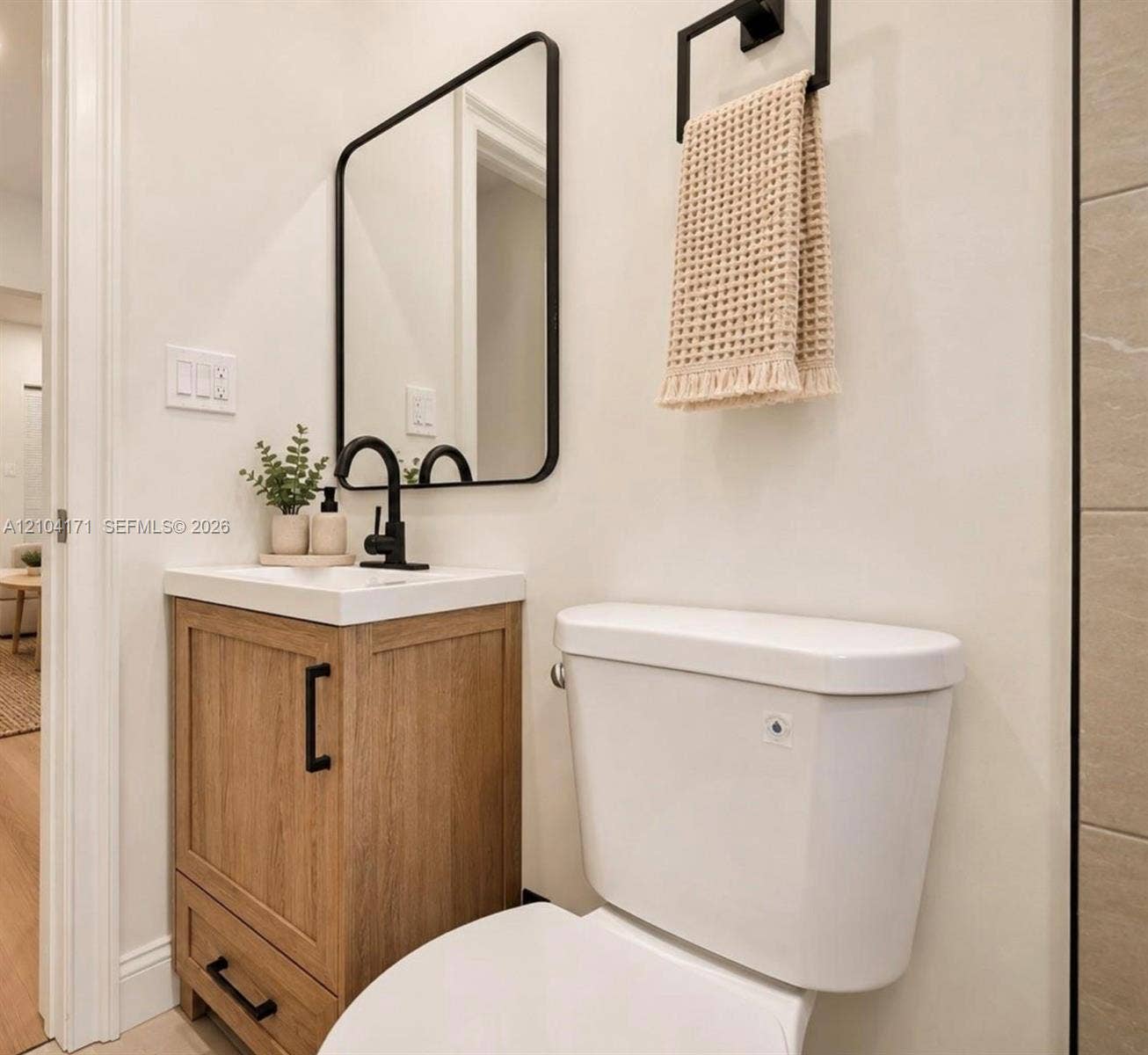 745 NW 32nd Avenue, Miami, FL 33125 Wood-finish vanity with a rectangular sink, matte black faucet, rounded rectangular mirror, and matte black towel hardware