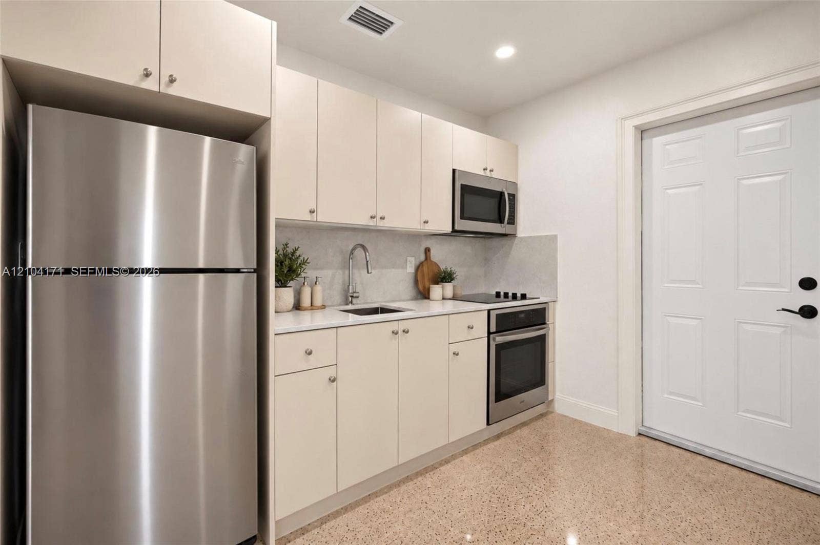 745 NW 32nd Avenue, Miami, FL 33125 Kitchen featuring flat-panel cabinetry, stainless steel appliances, light-toned stone-finish countertops, and polished composite flooring