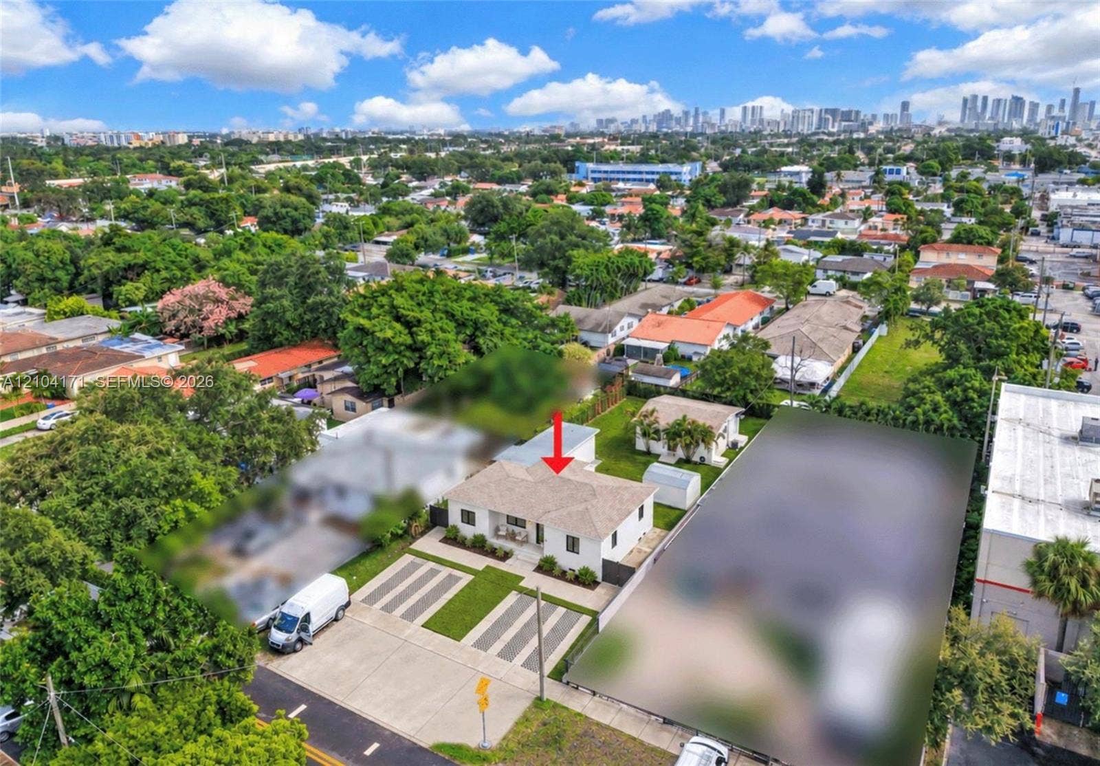 745 NW 32nd Avenue, Miami, FL 33125 Single-story residence featuring a light-colored exterior, a multi-pitched shingle roof, and a paved multi-car driveway with integrated grass strips