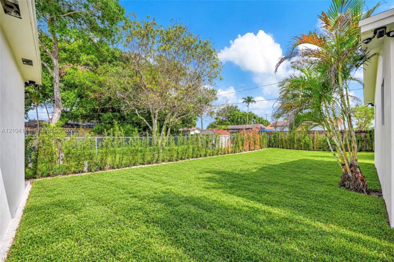 745 NW 32nd Avenue, Miami, FL 33125 Backyard featuring a manicured lawn, perimeter fencing, and established landscape greenery