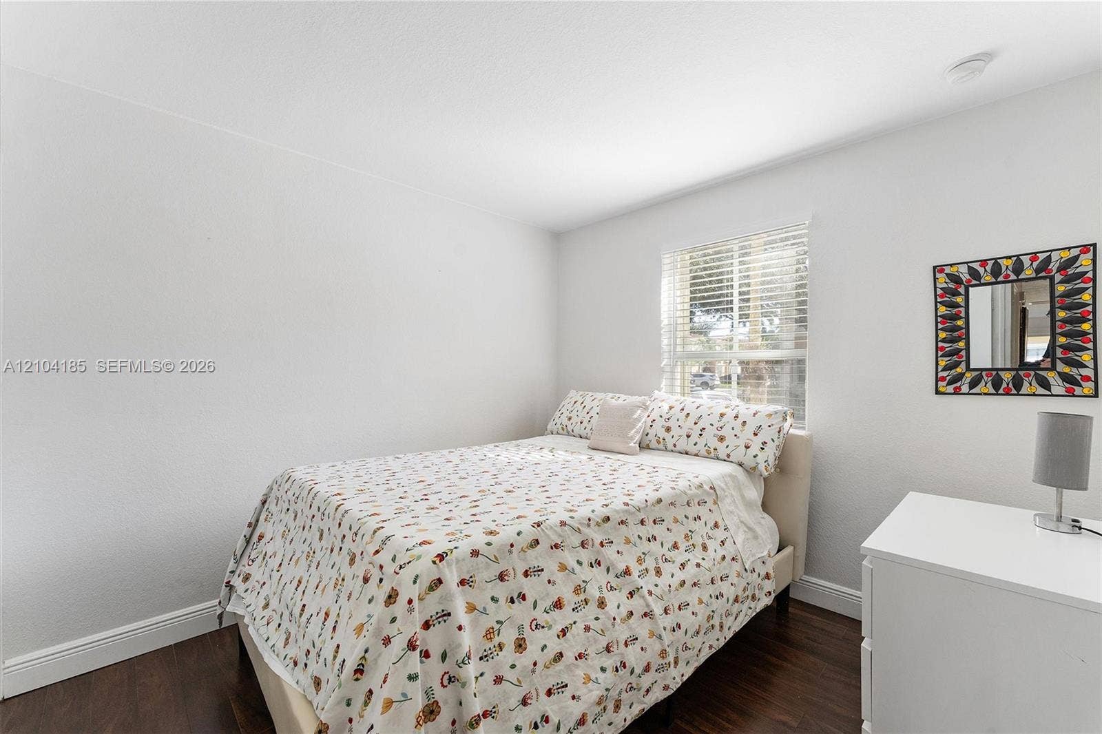 Room featuring wood-finish flooring, a neutral color palette, and a window with horizontal blinds