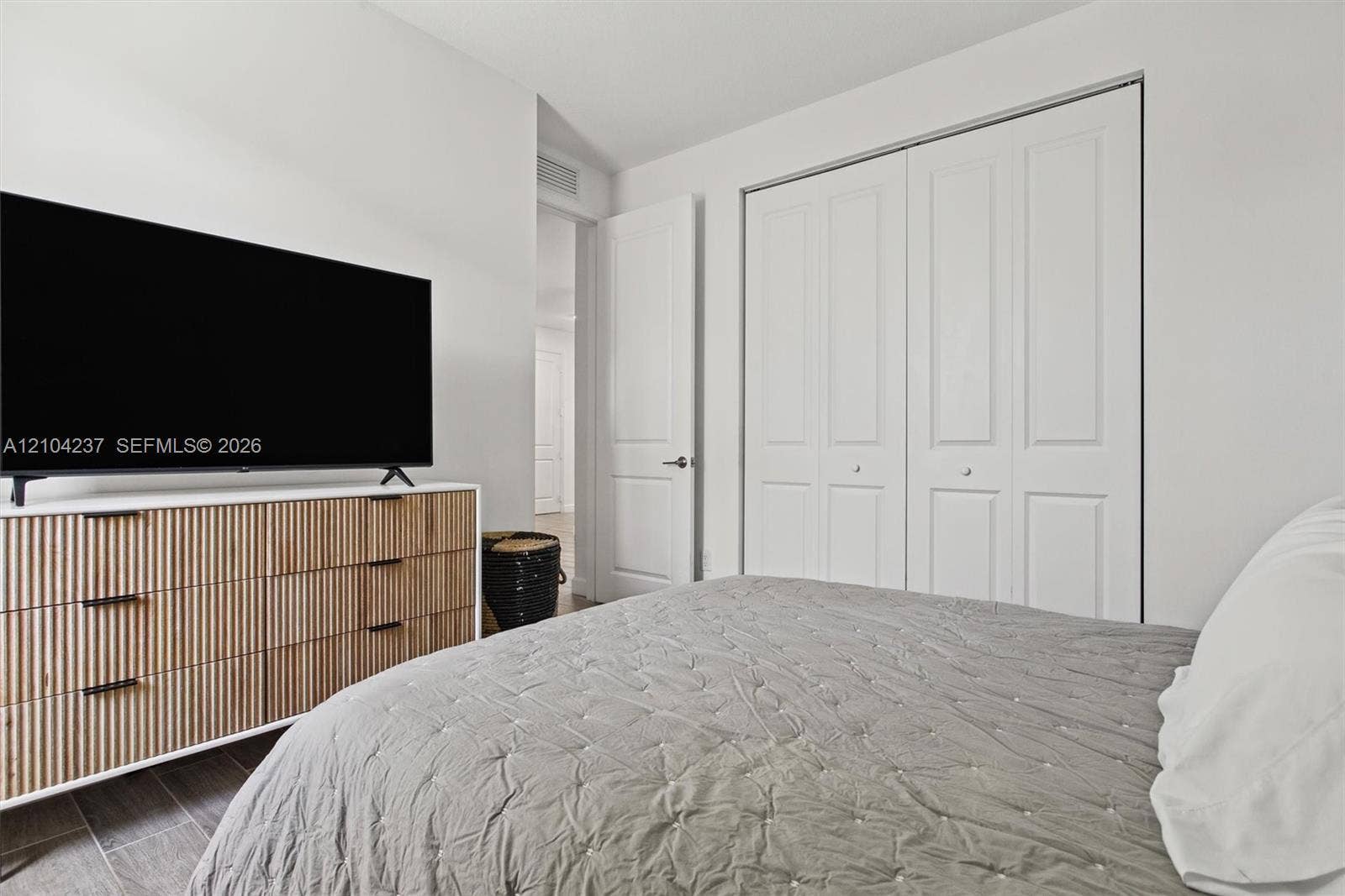 Interior space featuring double-panel bi-fold closet doors, solid-core doors with matte black hardware, and wood-finish tile flooring