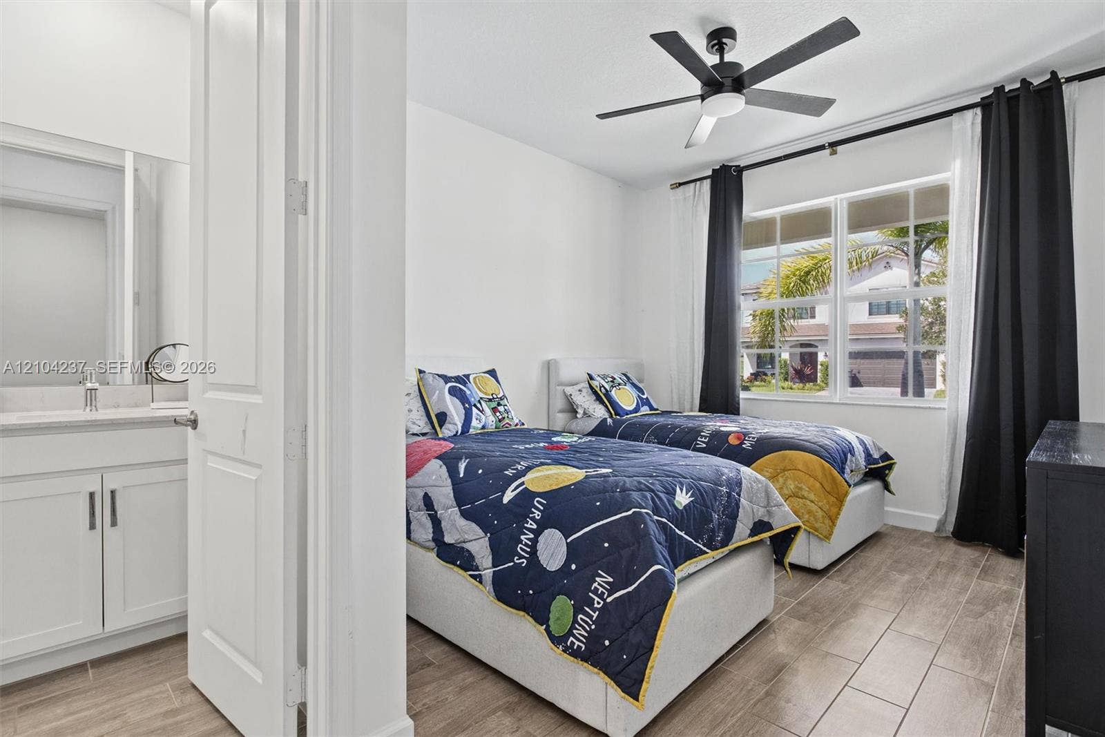 Wood-finish tile flooring, recessed ceiling fan with integrated lighting, multi-pane window with grid detailing, and white cabinetry featuring a stone-look countertop and wall-mounted mirror