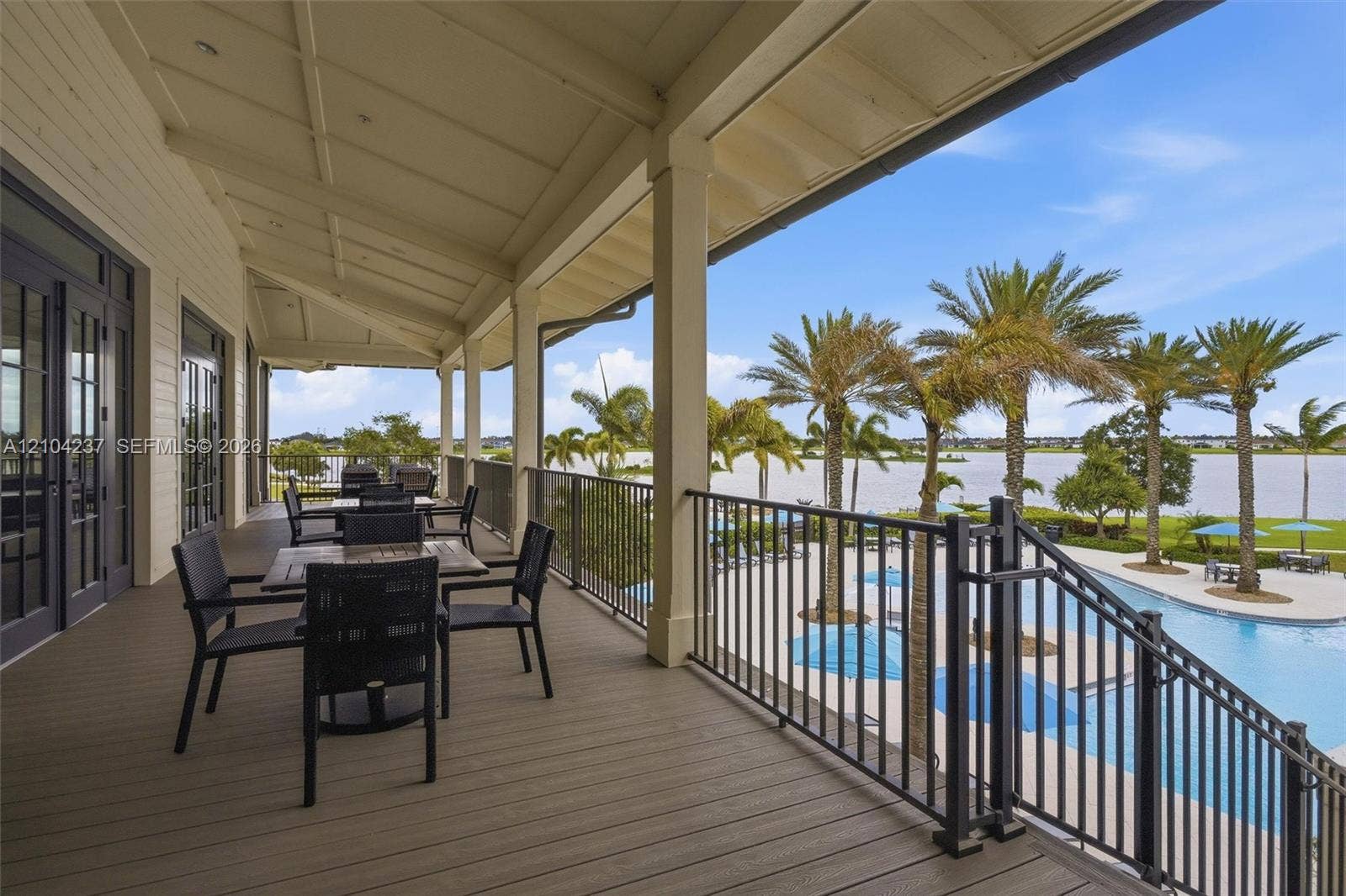 Covered balcony featuring composite decking, recessed ceiling lighting, black metal railing, and direct water exposure