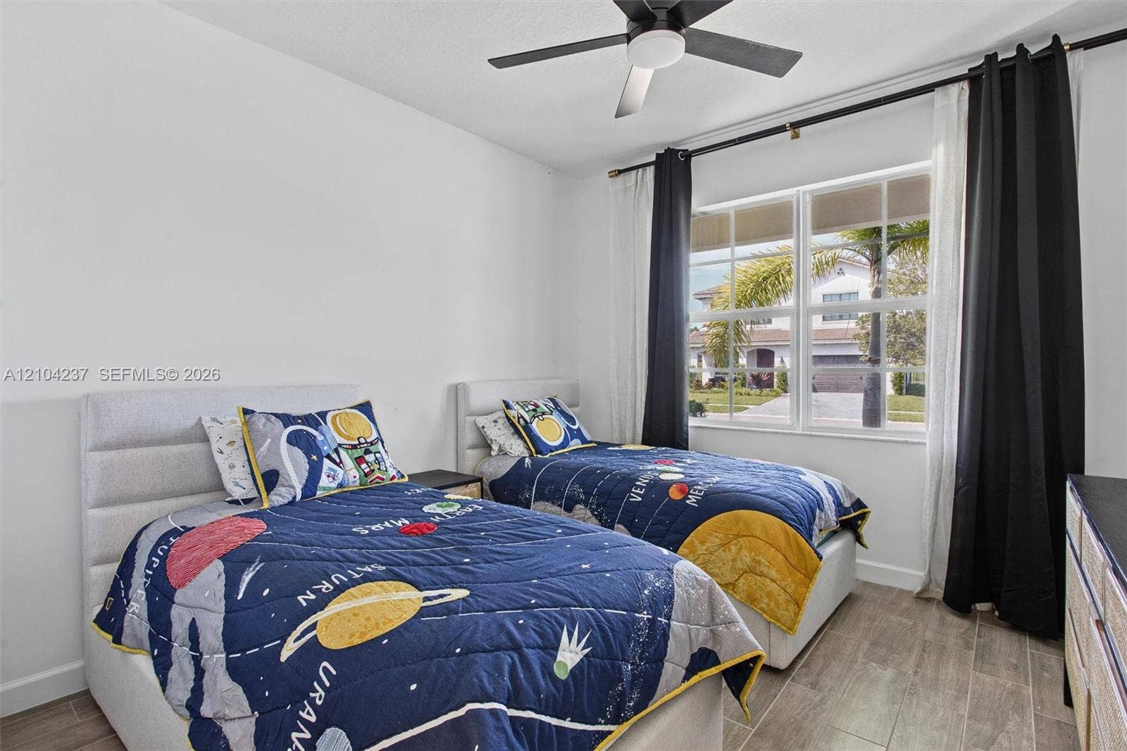 Interior room featuring wood-finish tile flooring, a multi-pane window with white trim, and a ceiling fan with integrated lighting