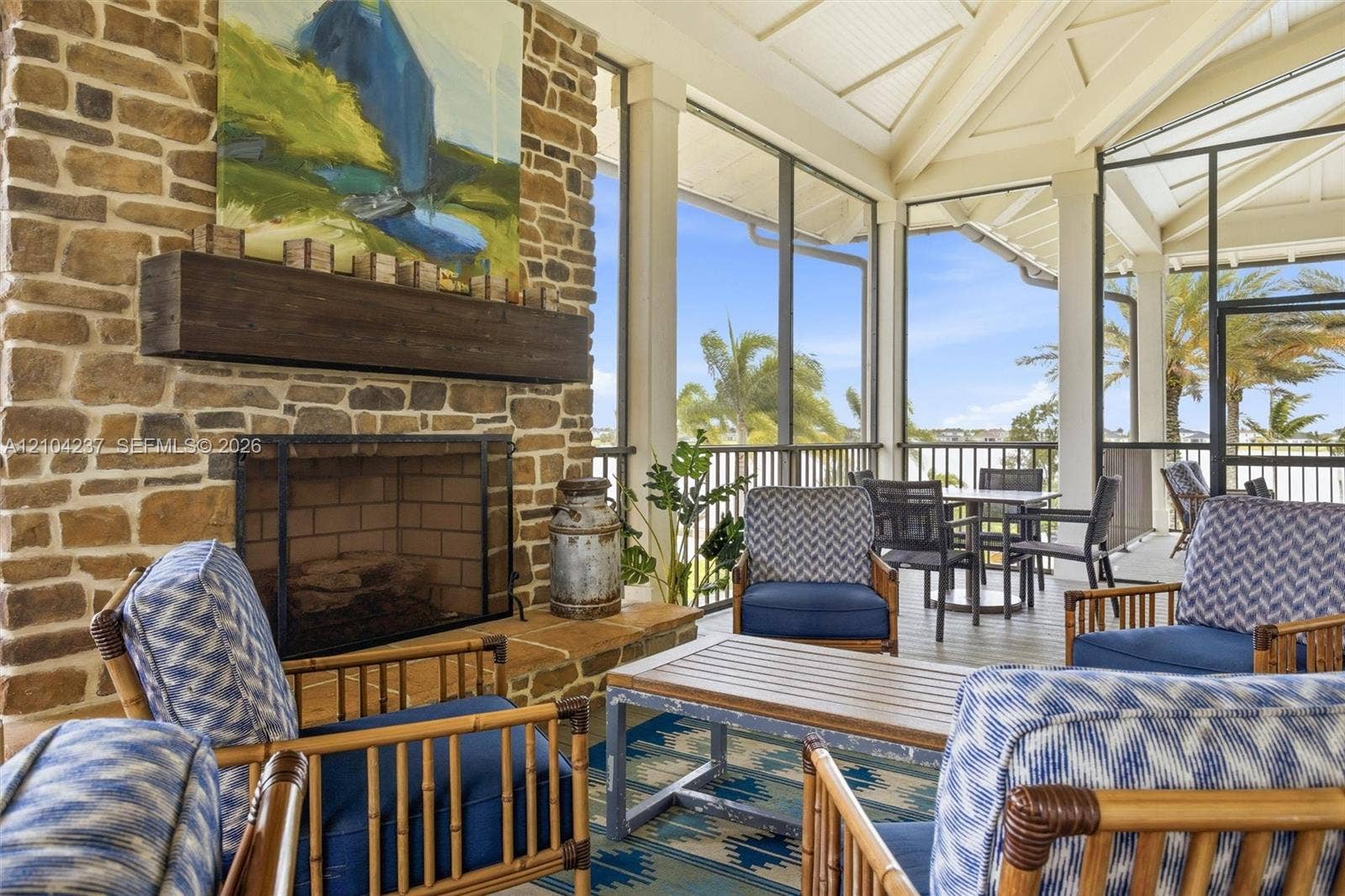 Screened porch featuring a stone fireplace with a thick timber mantel, vaulted ceiling, and exterior lattice screening