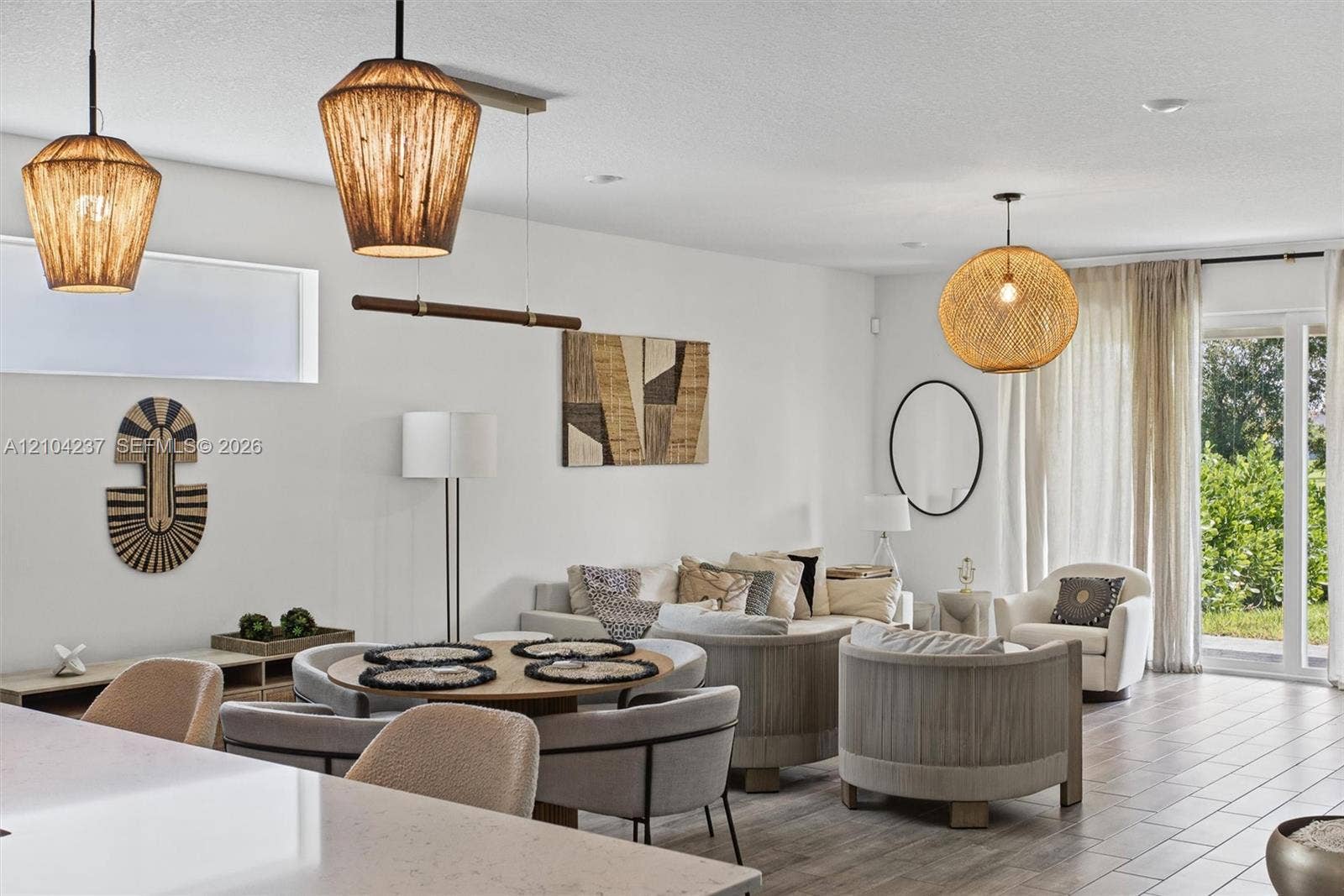Open-concept interior featuring light wood-finish flooring, recessed lighting, and three textured pendant light fixtures