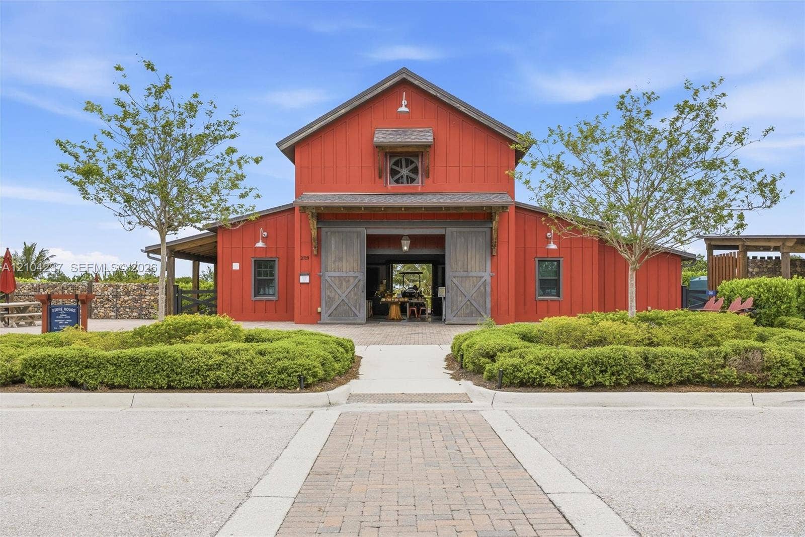 Barn-style exterior featuring vertical wood siding, large sliding barn doors, overhanging eaves with decorative corbels, and a central gable dormer