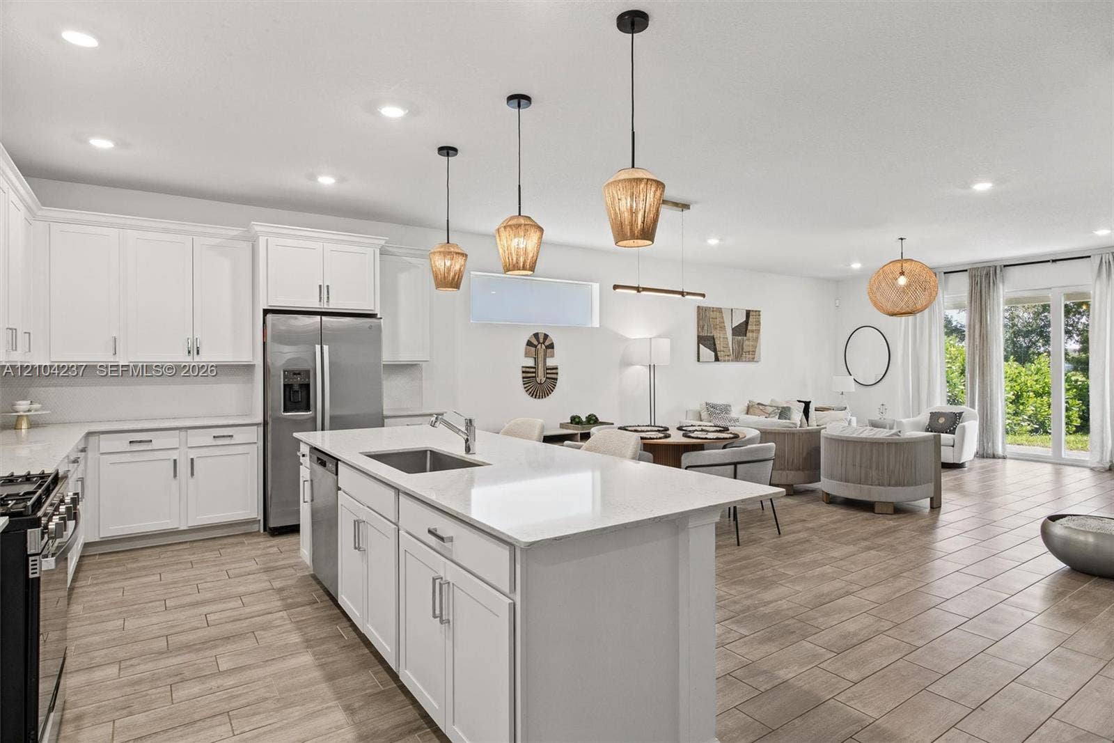 Kitchen featuring white cabinetry, stone-surface countertops, center island with stainless steel undermount sink, recessed lighting, and wood-finish tile flooring