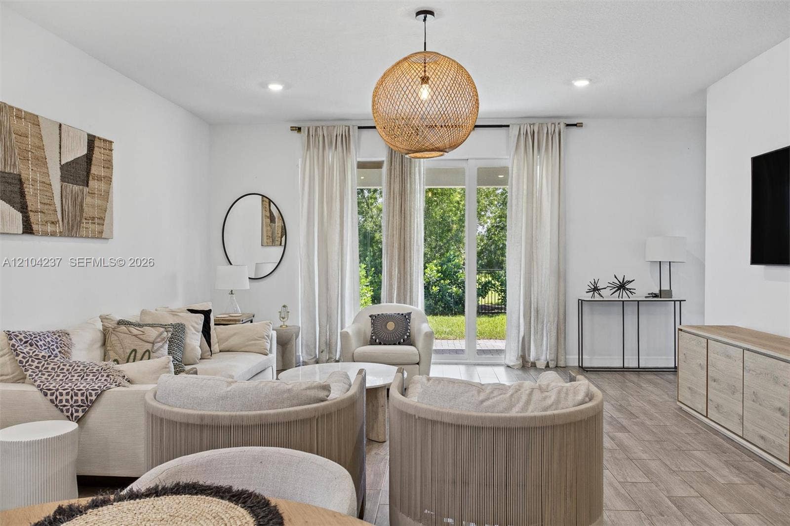 Living area featuring wood-finish tile flooring, recessed lighting, a statement woven pendant light fixture, and glass-paneled doors