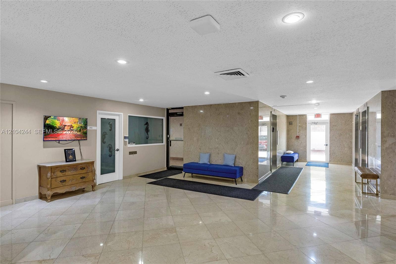 Lobby featuring polished stone floor tiling, stone-clad wall accents, recessed lighting, and metal elevator doors