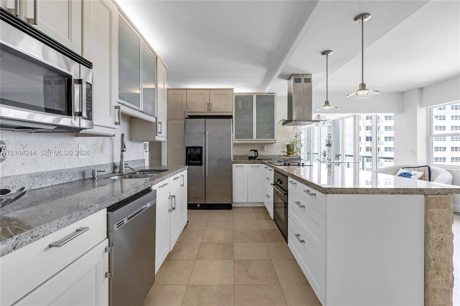Kitchen featuring flat-panel cabinetry, stone countertops, stainless steel appliances, a center island with pendant lighting, and tile flooring