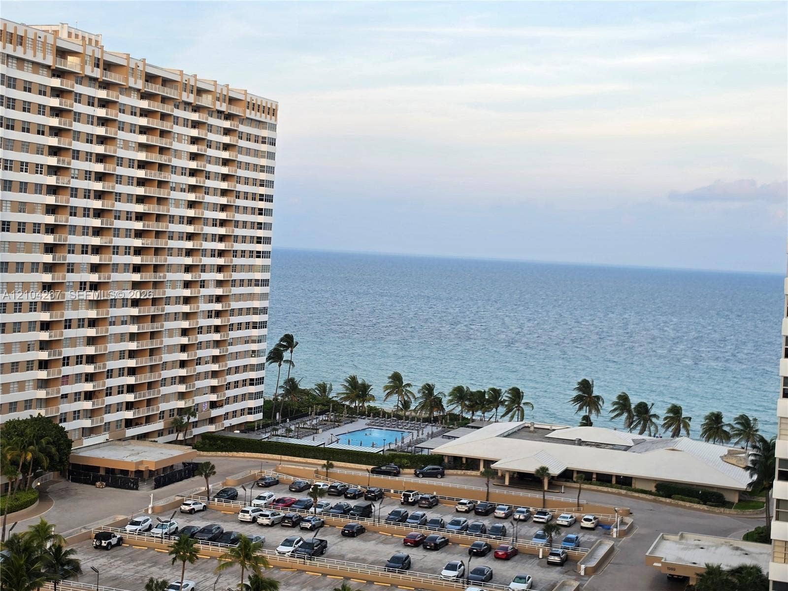 High-rise exterior featuring private balconies, an outdoor swimming pool, and oceanfront placement
