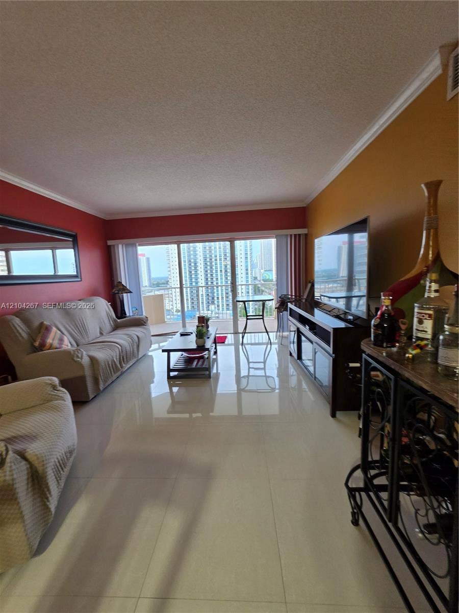 Polished tile flooring, crown molding, and floor-to-ceiling glass sliding doors opening to a balcony