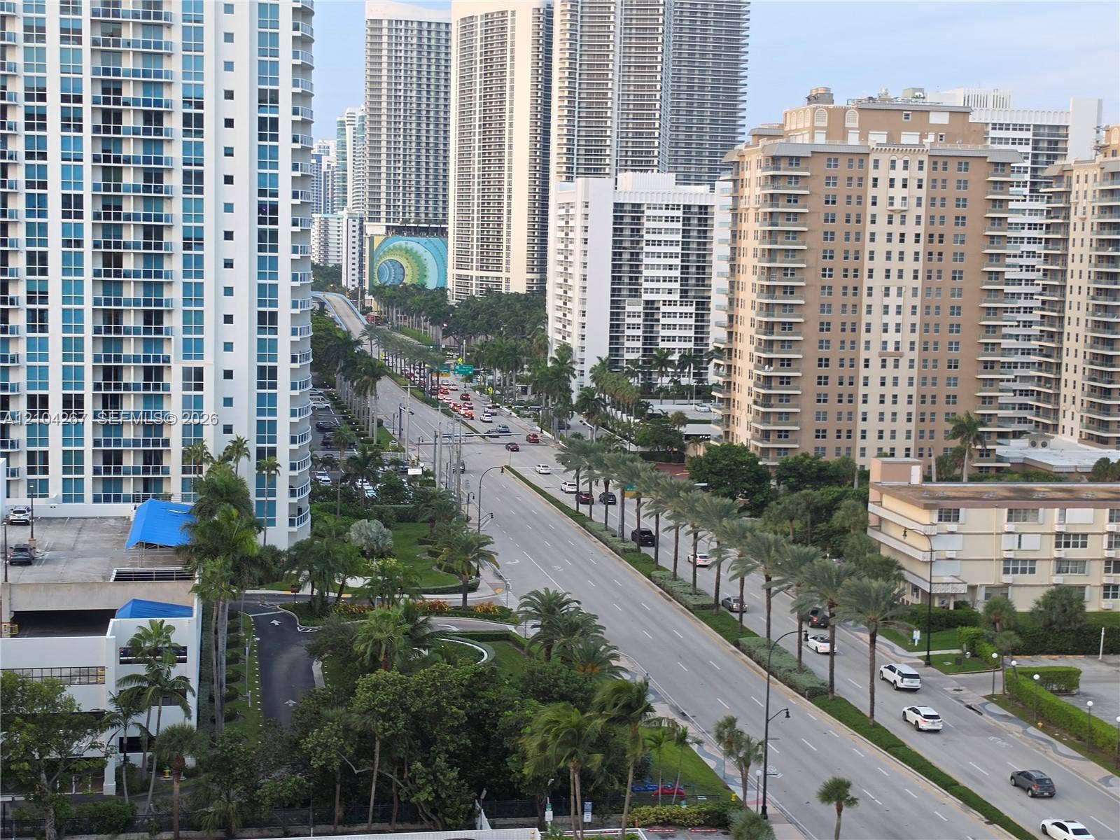 Urban setting featuring high-rise buildings, multi-lane thoroughfare, and mature palm tree landscaping