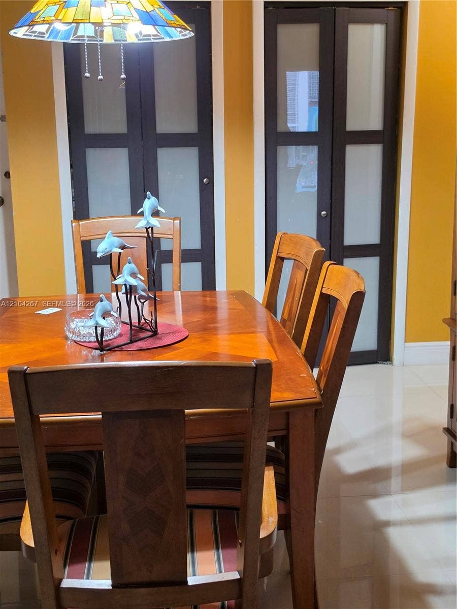 Dual bi-fold doors featuring dark frames and frosted glass panels, complemented by polished tile flooring and a stained-glass pendant light fixture