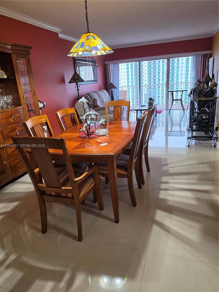 Polished ceramic tile flooring, expansive floor-to-ceiling glass sliding doors, crown molding, and a custom stained-glass pendant light fixture