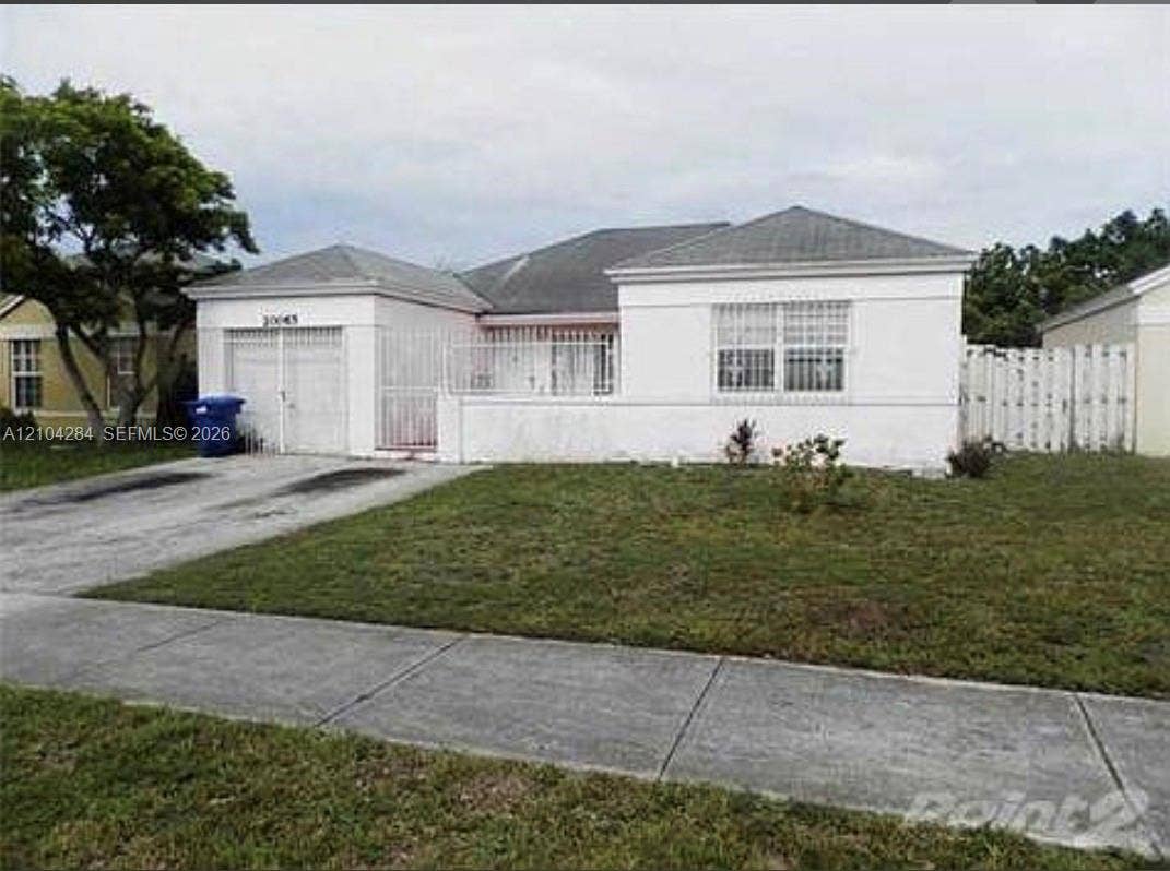 20065 NW 36 Avenue, Miami Gardens, Miami Gardens, FL 33056 Single-story stucco exterior featuring a hipped roof, attached garage, metal security window bars, and perimeter fencing