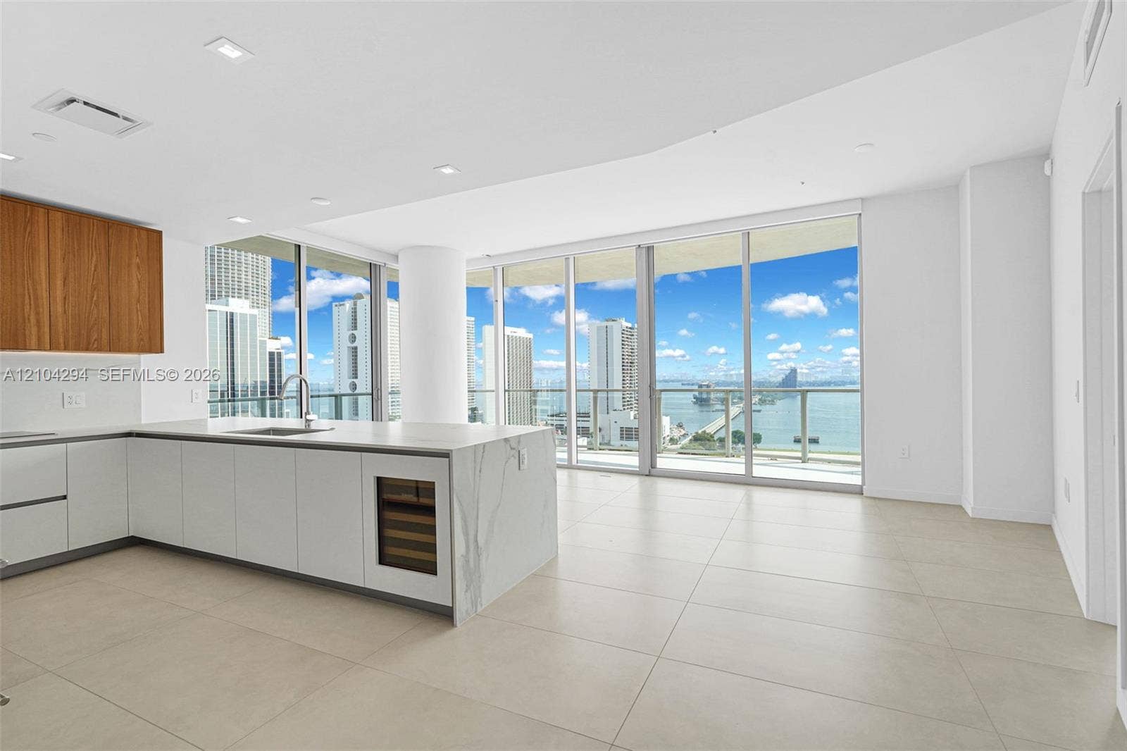 1400 Biscayne Boulevard, #1606, Miami, FL 33132 Modern kitchen featuring a waterfall island with a built-in wine cooler, wood-finish upper cabinetry, and white lower cabinetry