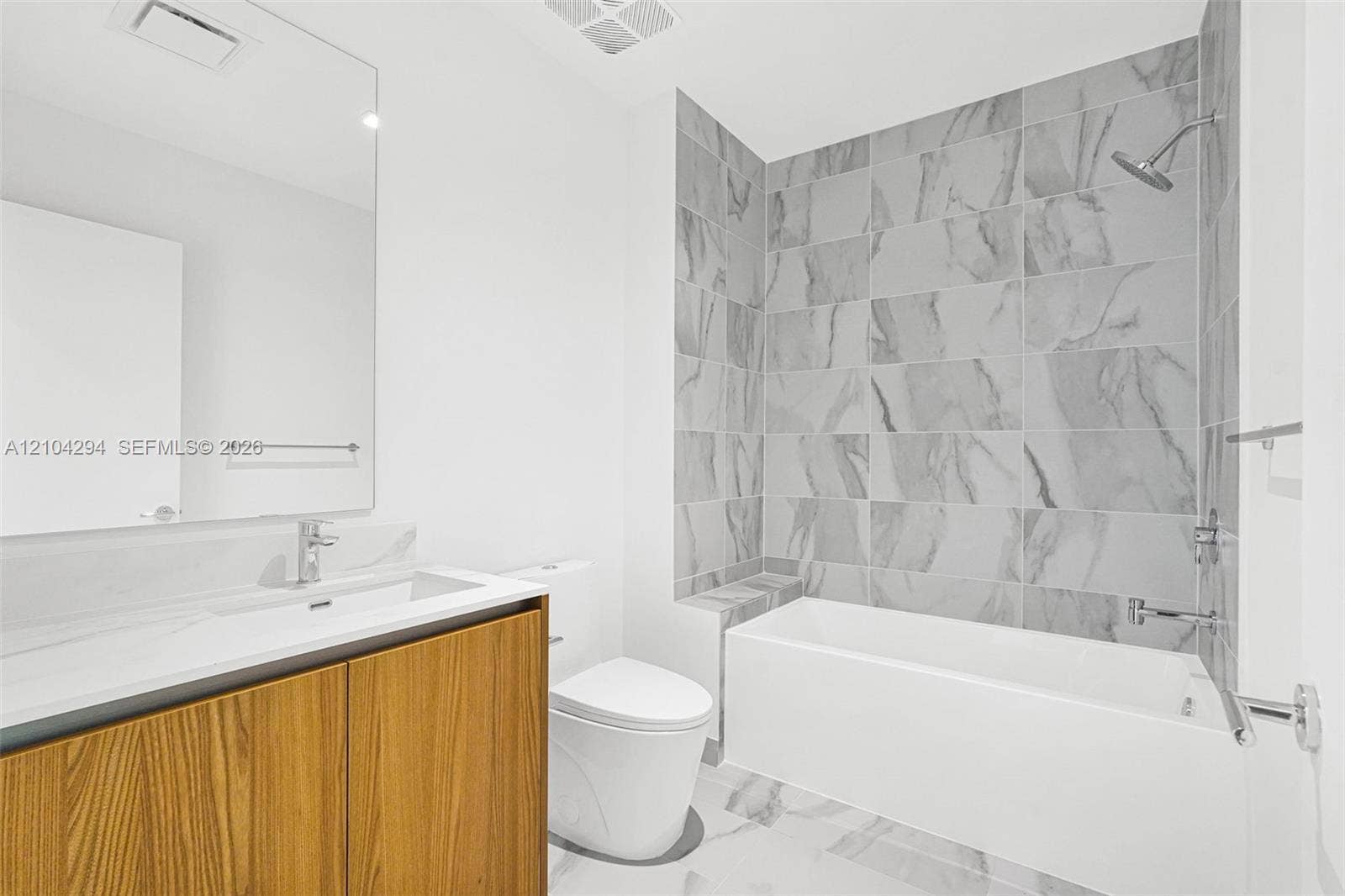 1400 Biscayne Boulevard, #1606, Miami, FL 33132 Bathroom featuring a floating wood-finish vanity, integrated sink, large format tile flooring, and a tiled shower with an integrated bench