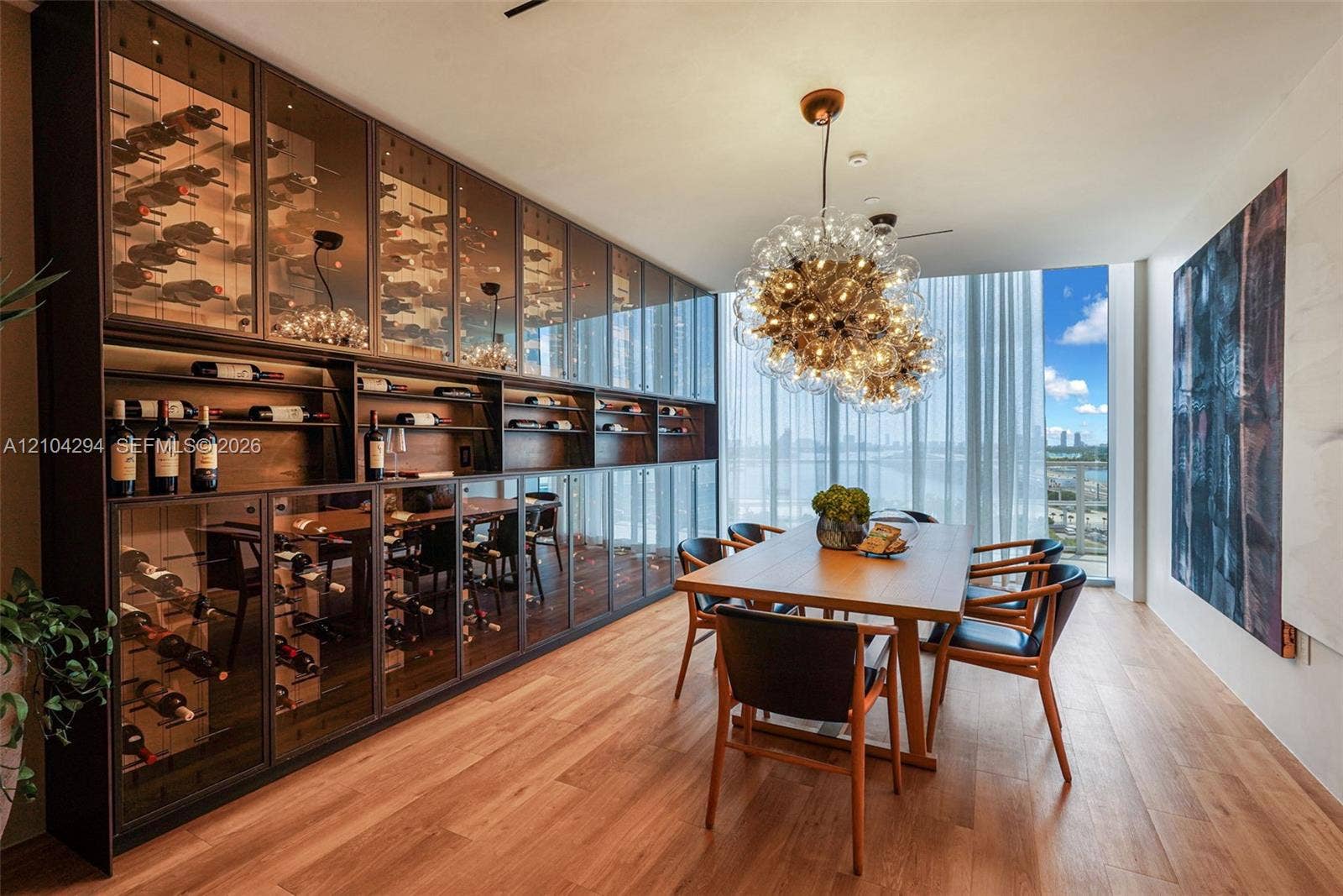 1400 Biscayne Boulevard, #1606, Miami, FL 33132 Built-in wine storage cabinetry with glass-front doors, wood-finish flooring, full-height windows, and a contemporary chandelier