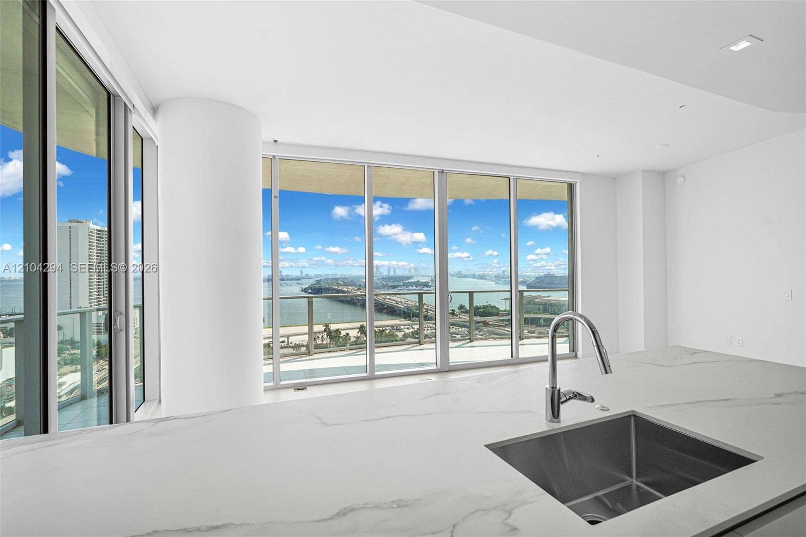 1400 Biscayne Boulevard, #1606, Miami, FL 33132 Expansive floor-to-ceiling windows, white countertop with veining, under-mount stainless steel sink, contemporary chrome pull-down faucet, recessed ceiling lighting