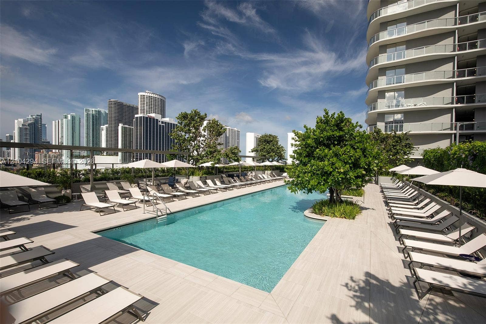 1400 Biscayne Boulevard, #1606, Miami, FL 33132 Swimming pool featuring a large concrete deck, integrated mature landscaping, and an expansive cityscape backdrop