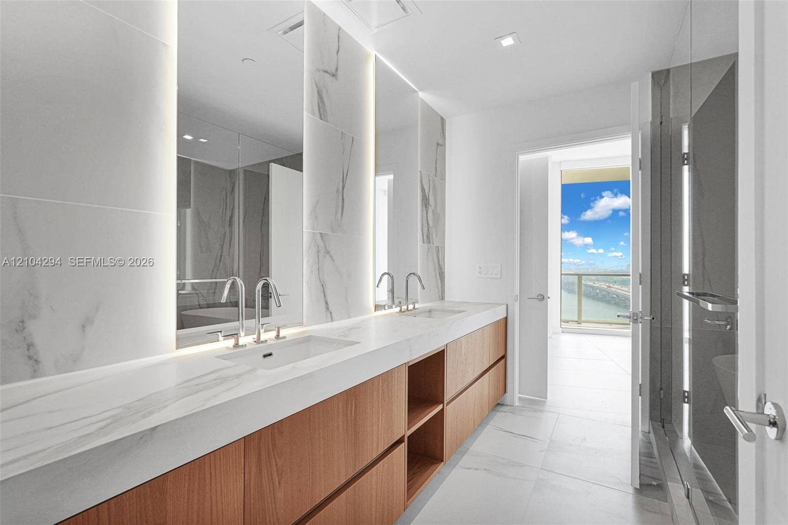 1400 Biscayne Boulevard, #1606, Miami, FL 33132 Dual vanity with integrated sinks, wood-finish cabinetry, polished chrome fixtures, and large format wall and floor tiling