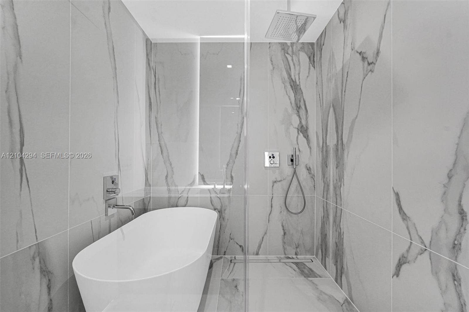 1400 Biscayne Boulevard, #1606, Miami, FL 33132 Freestanding soaking tub, walk-in shower, rain shower head, hand-held shower, and wall-mounted plumbing fixtures, all surrounded by large-format porcelain tile