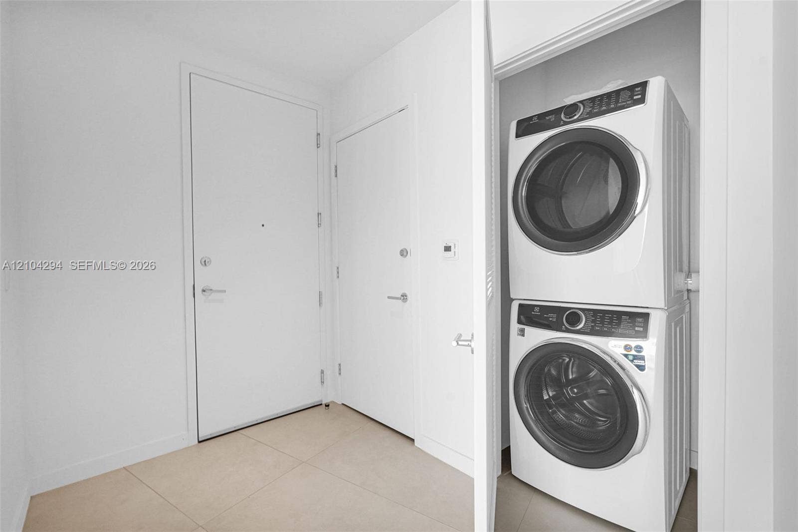 1400 Biscayne Boulevard, #1606, Miami, FL 33132 Stacked washer and dryer unit, smooth white walls, and light-toned floor tiling