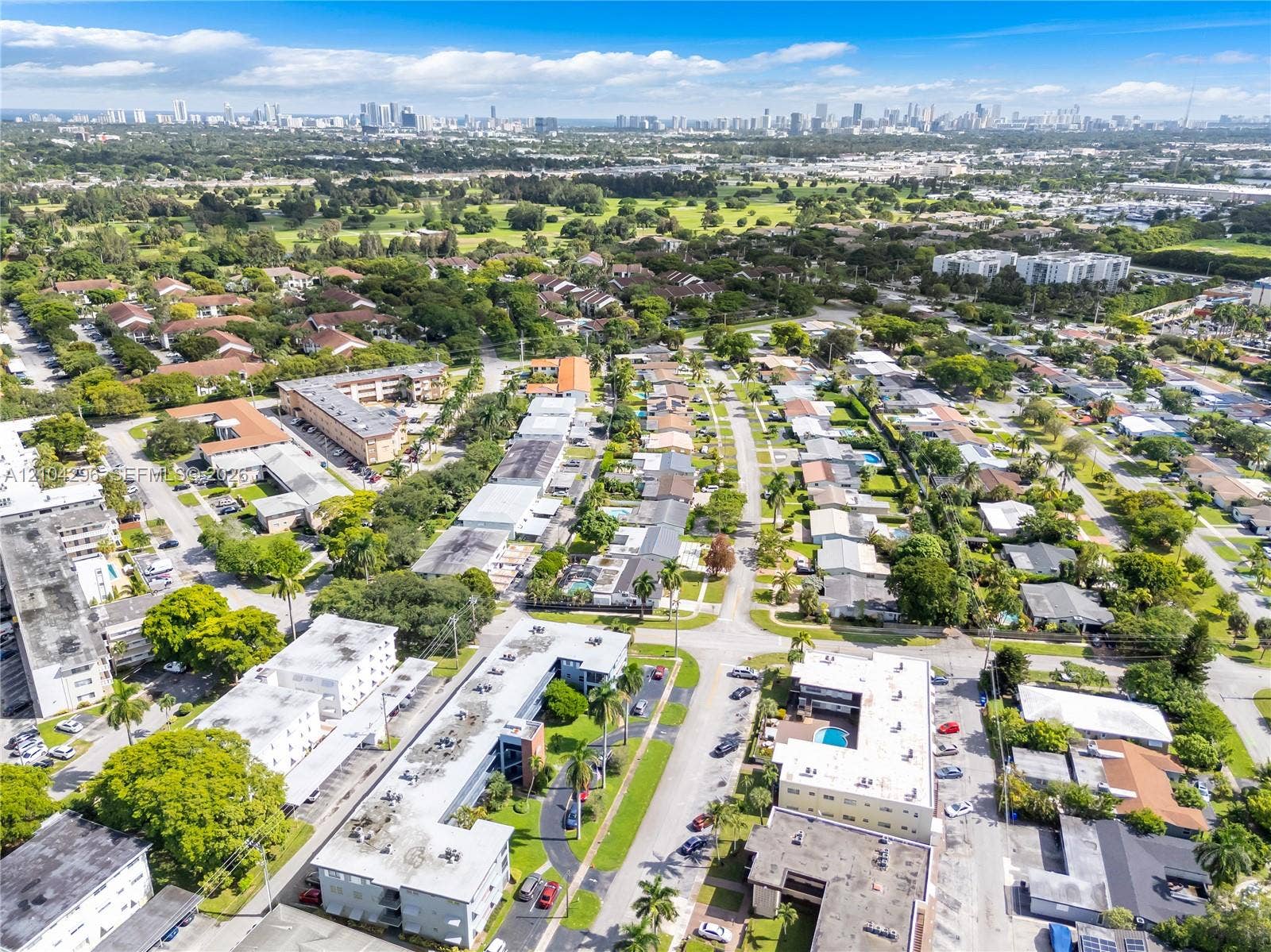 Aerial perspective of the residential grounds featuring mature shade trees, paved walkways, and multiple swimming pools