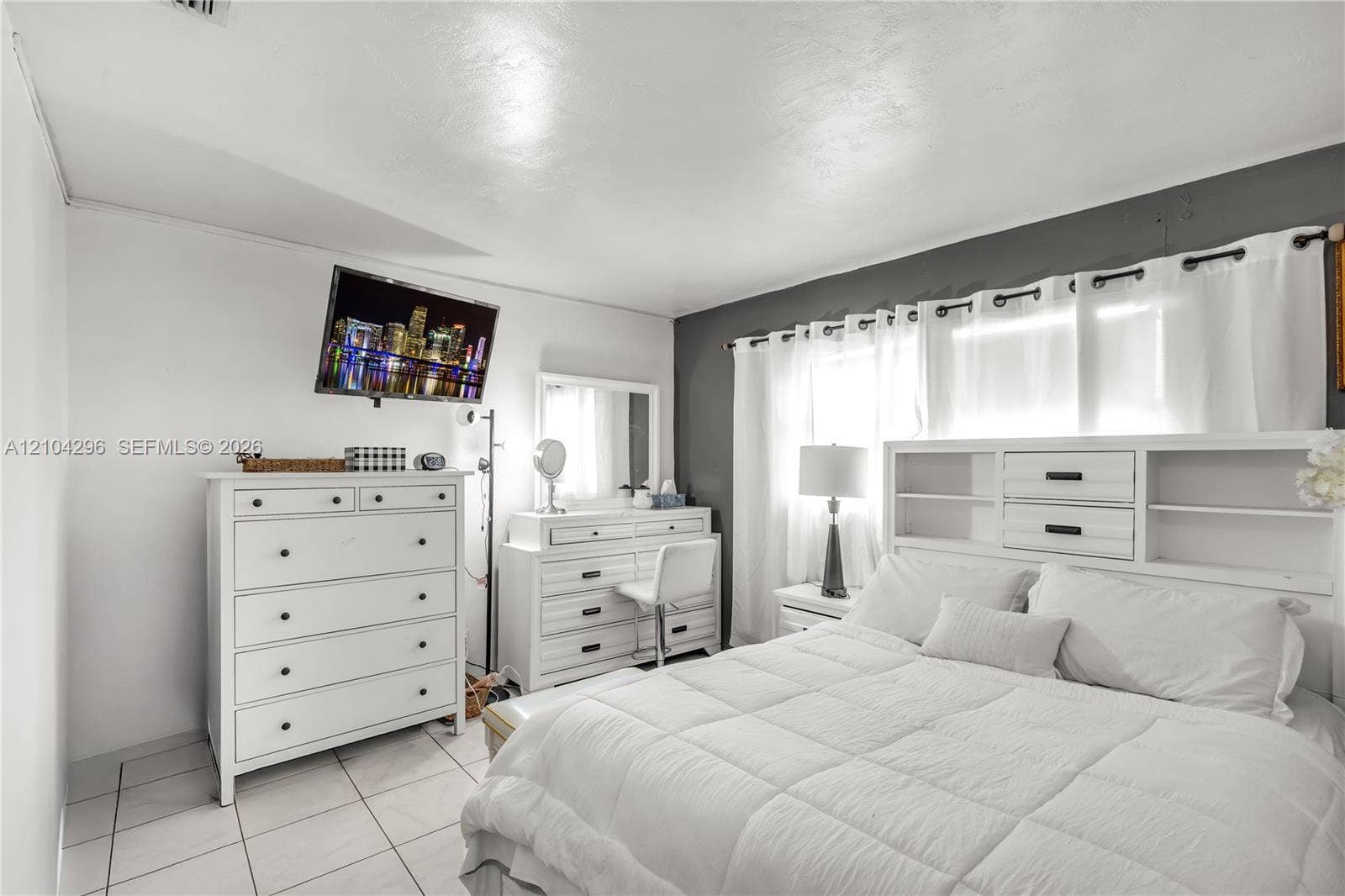 Room featuring light-colored tile flooring, a dual-tone wall finish, and an integrated curtain rod system
