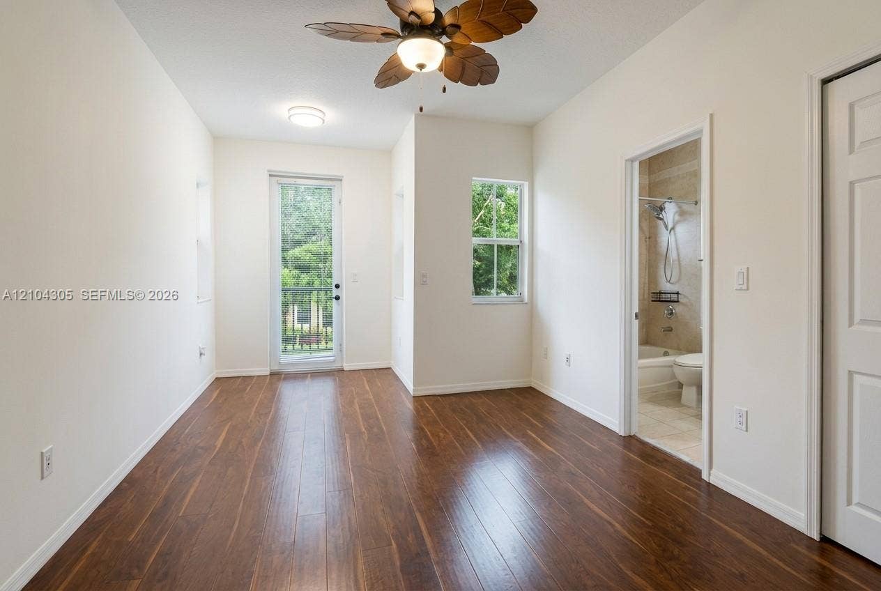 15261 SW 26th Terrace, Miami, FL 33185 Room featuring wood-finish flooring, ceiling fan with palm-style blades, single-pane windows, glass-panel entry door, and multi-panel interior door
