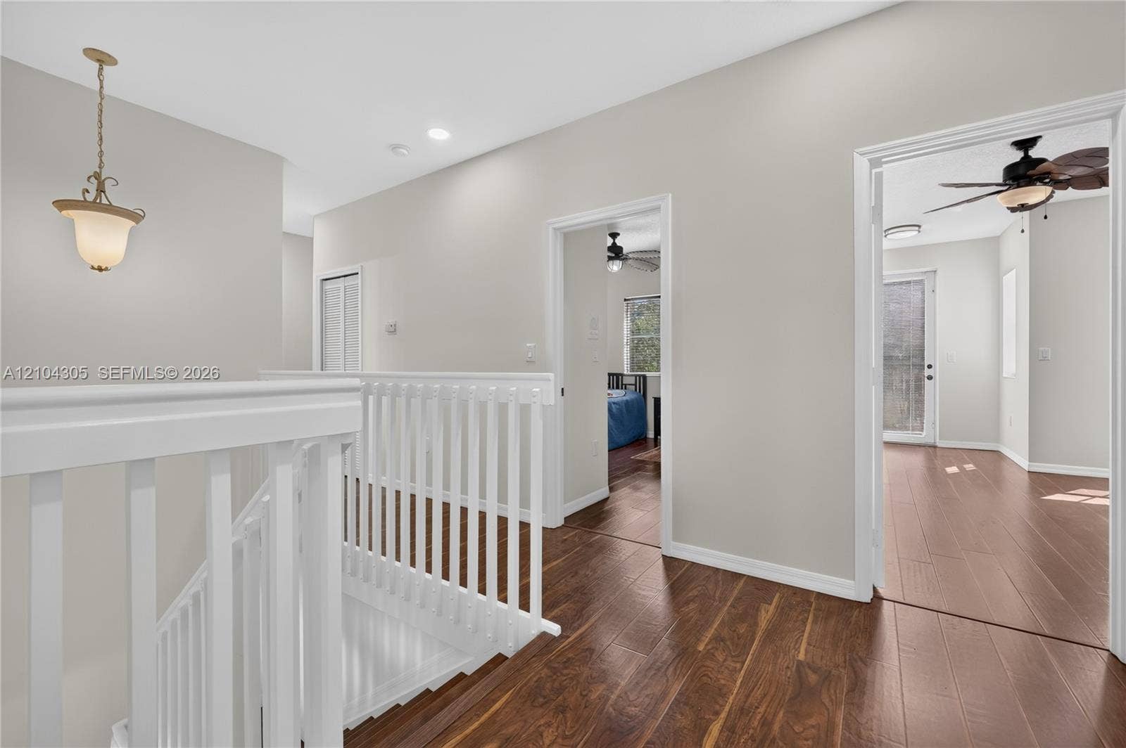 15261 SW 26th Terrace, Miami, FL 33185 Hallway featuring wood-finish flooring, white spindle balustrades, neutral paint palette, recessed lighting, and a pendant light fixture