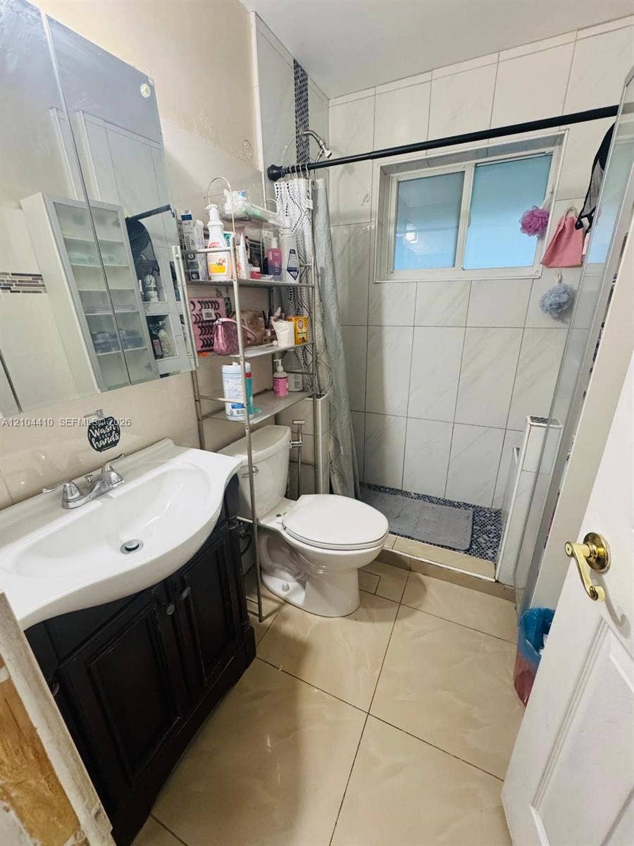 2312 Van Buren Street, #2, Hollywood, Hollywood, FL 33020 Bathroom featuring a dark-finish vanity with an integrated basin, large-format tile flooring, wall-tiled shower enclosure, and mirrored medicine cabinet