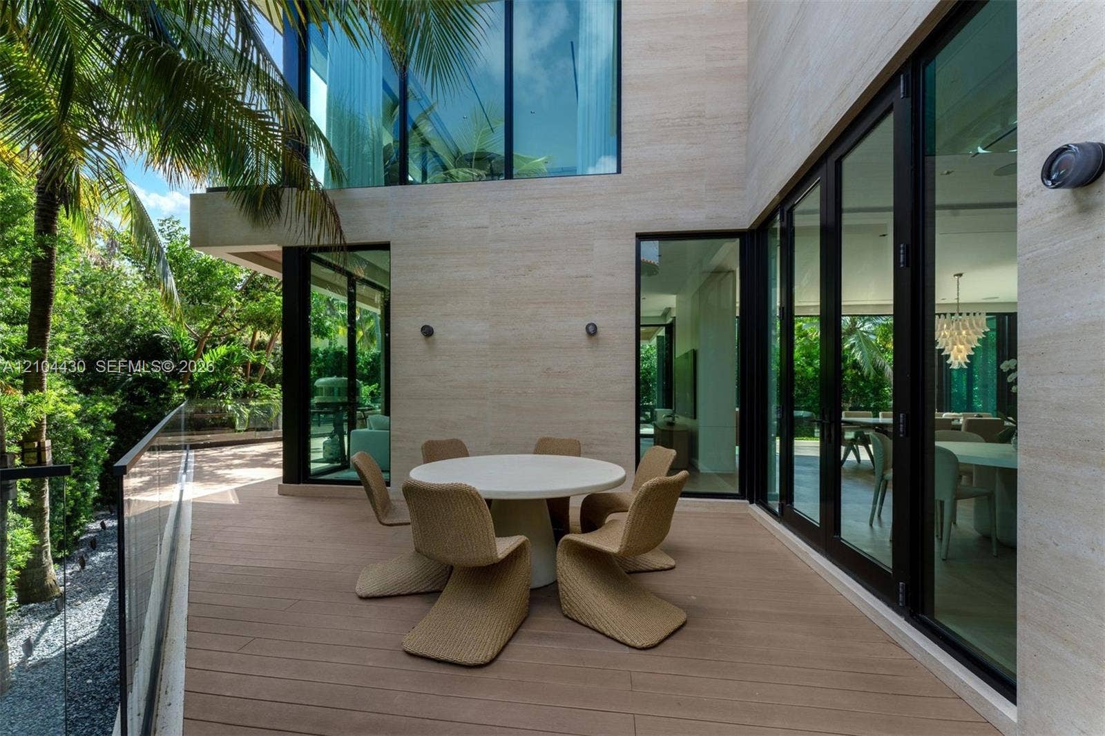 Modern terrace featuring natural stone wall cladding, wood-finish decking, black-framed floor-to-ceiling glass panels, and a frameless glass railing