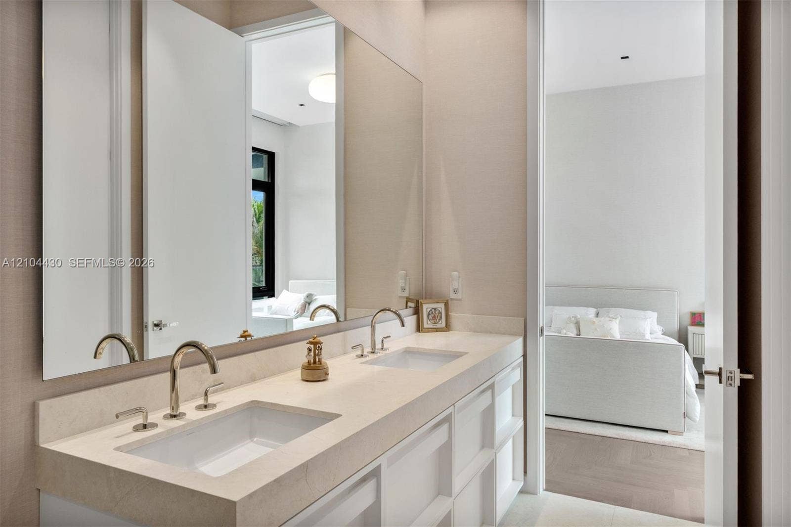 Dual-sink vanity with a solid-surface countertop, rectangular under-mount basins, polished metal gooseneck faucets, and a full-width wall mirror