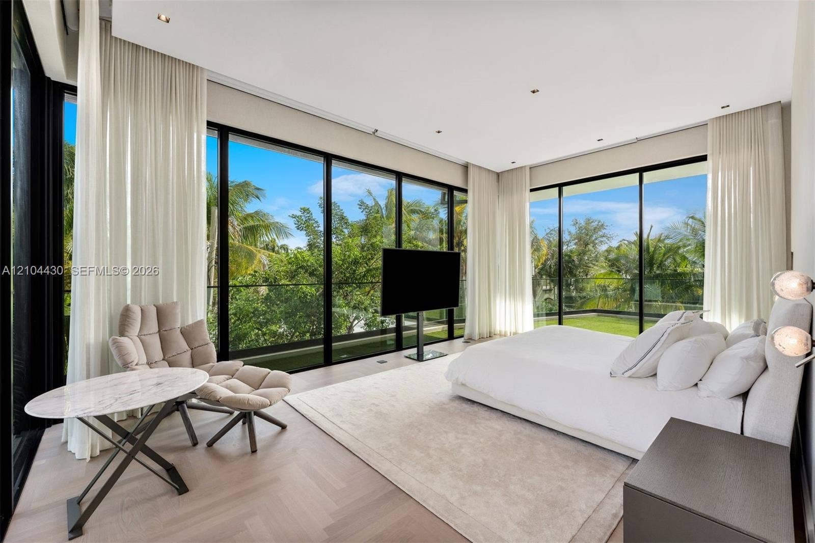 Floor-to-ceiling black-framed windows, herringbone-pattern wood-finish flooring, recessed lighting, and integrated drapery tracks