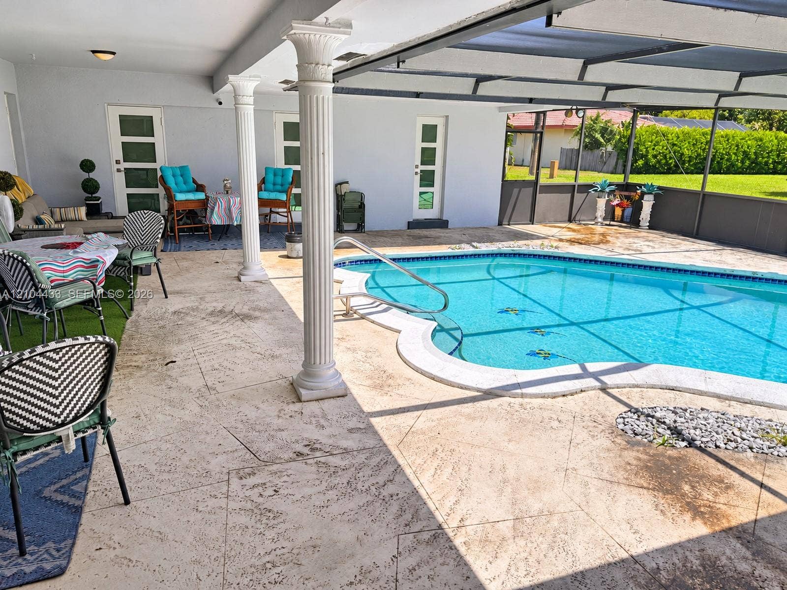 7380 NW 9th Street, Plantation, FL 33317 Expansive outdoor patio with a freeform swimming pool, decorative columns, and a screened enclosure