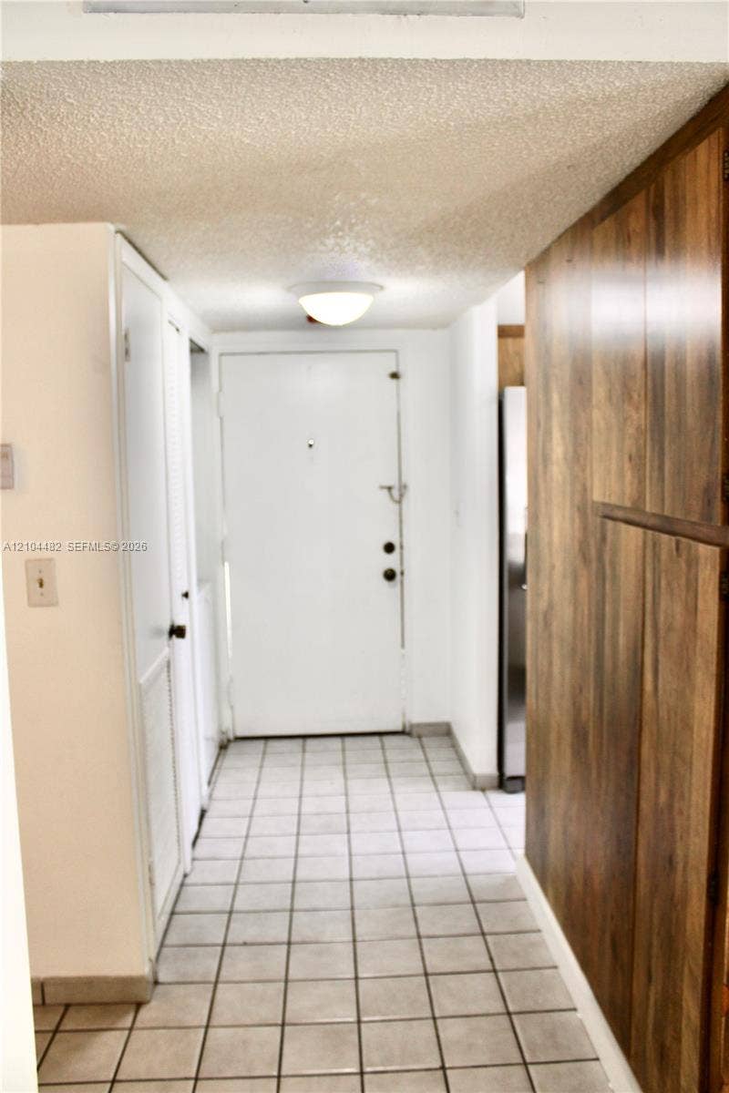 18000 NW 68th Avenue, #409A, Hialeah, Hialeah, FL 33015 Entryway featuring square ceramic tile flooring, wood-finish wall paneling, built-in cabinetry, and a flush-mount ceiling light fixture