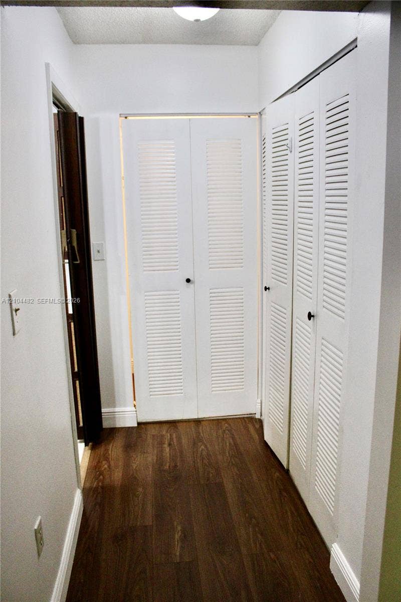 18000 NW 68th Avenue, #409A, Hialeah, Hialeah, FL 33015 Hallway featuring wood-finish flooring and multiple white louvered bifold doors