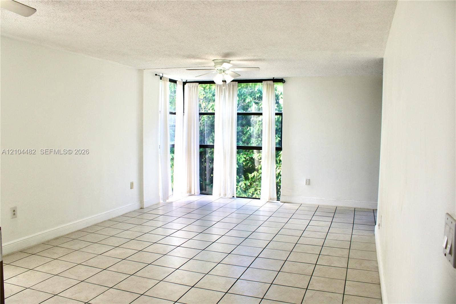 18000 NW 68th Avenue, #409A, Hialeah, Hialeah, FL 33015 Interior space featuring ceramic tile flooring, a multi-panel floor-to-ceiling window arrangement, and a centrally mounted ceiling fan
