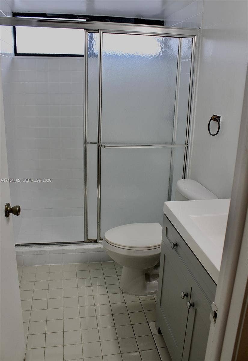 18000 NW 68th Avenue, #409A, Hialeah, Hialeah, FL 33015 Bathroom featuring a gray vanity with an integrated sink, shower enclosure with sliding textured glass doors, tiled walls, and ceramic tile flooring