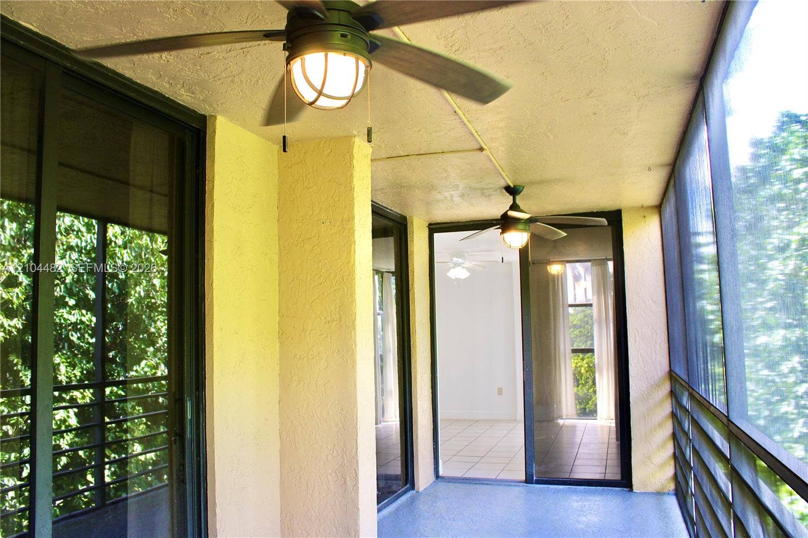 18000 NW 68th Avenue, #409A, Hialeah, Hialeah, FL 33015 Screened-in balcony featuring dual ceiling fans with integrated globe lighting, textured ceiling, and metal-frame screen enclosure