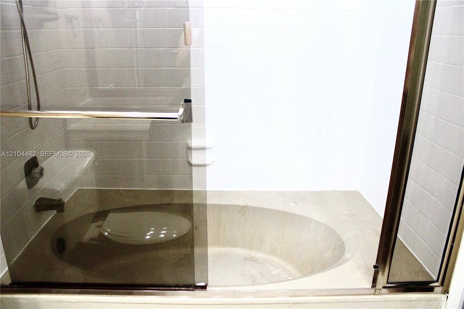 18000 NW 68th Avenue, #409A, Hialeah, Hialeah, FL 33015 Built-in oval soaking tub with stone-finish surround, sliding glass enclosure, white ceramic wall tile, and metallic hardware