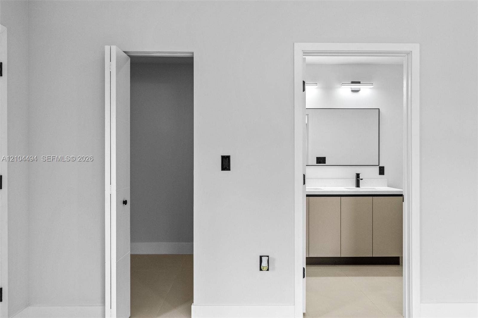 711 NW 8th Avenue, Dania Beach, FL 33004 Bathroom featuring a double-sink vanity with light-toned cabinetry, a rectangular mirror with a dark frame, wall-mounted light fixtures, and a matte black faucet